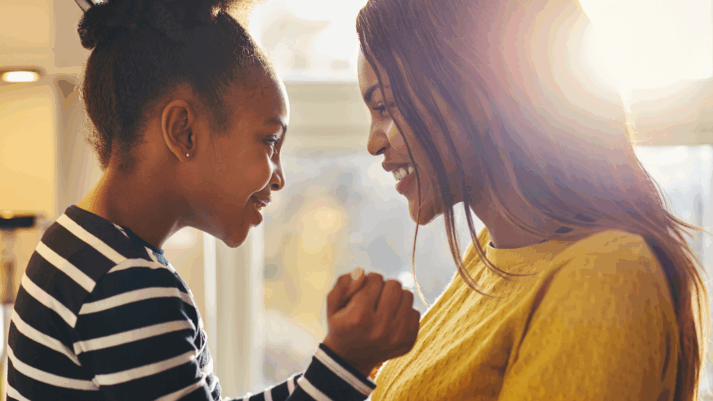mom and daughter smiling in front of a window
