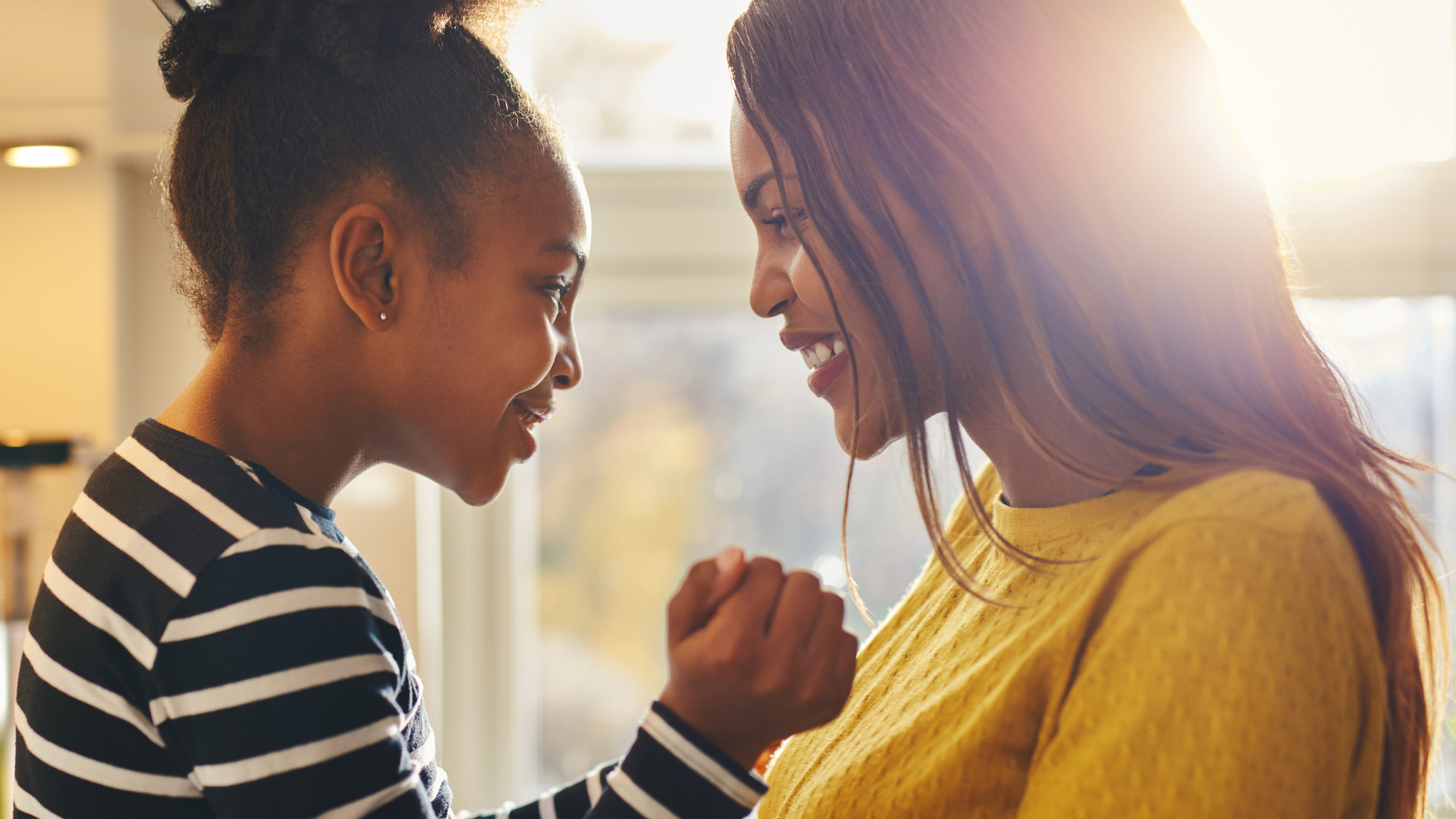 mom and daughter smiling in front of a window